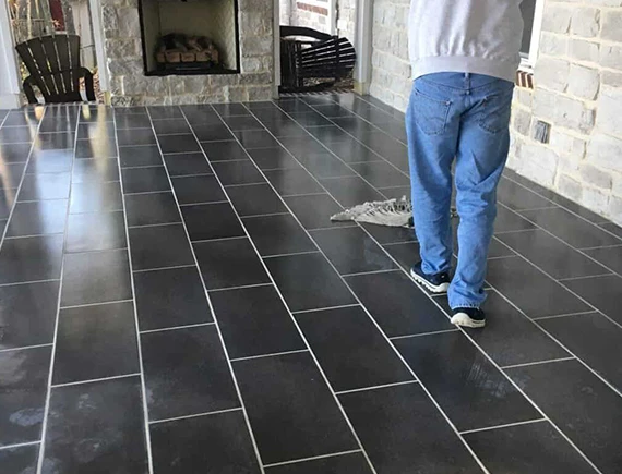 Handyman installing new black tile flooring in residential home, Boston MA